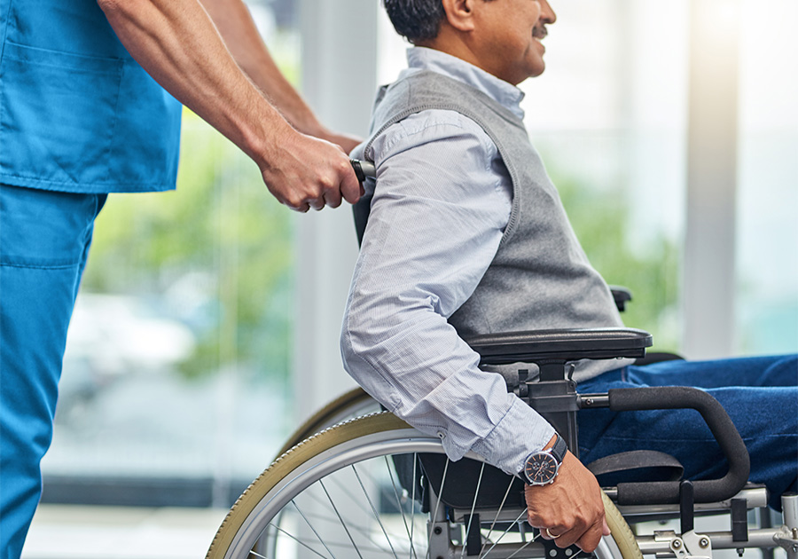 cropped image of male nurse pushing elderly man in wheelchair
