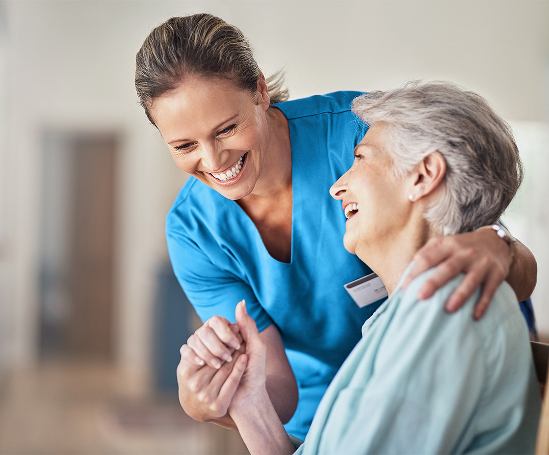 female nurse laughs with elderly woman